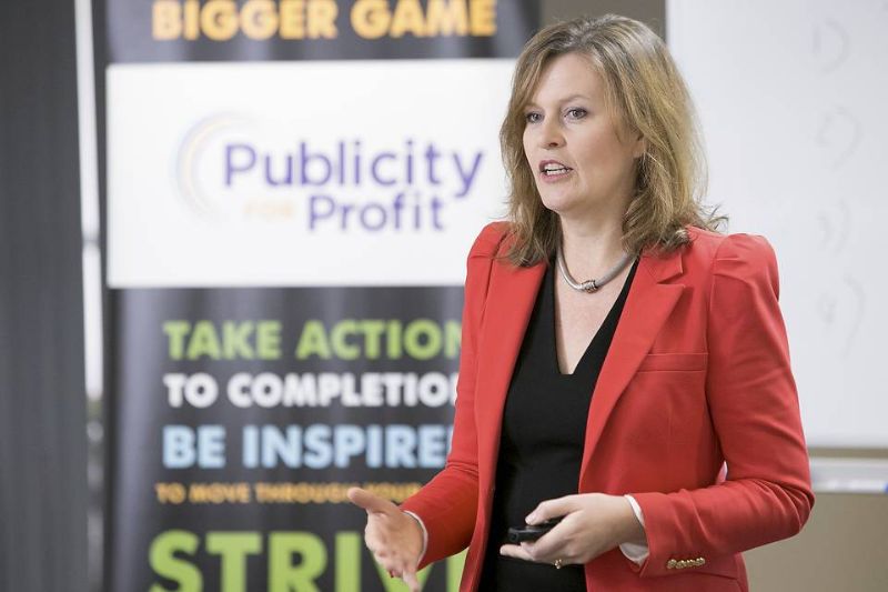 Woman in red jacket standing and speaking